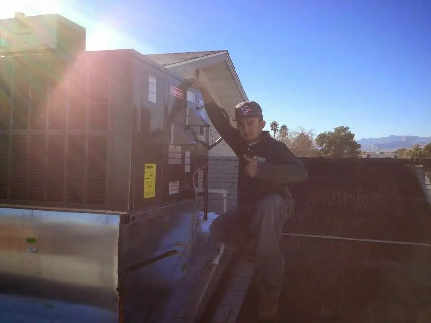 HVAC technician performing AC Tune-Up on a rooftop unit in Flint