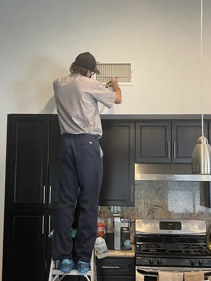 Technician inspecting an air vent during HVAC service in Flint